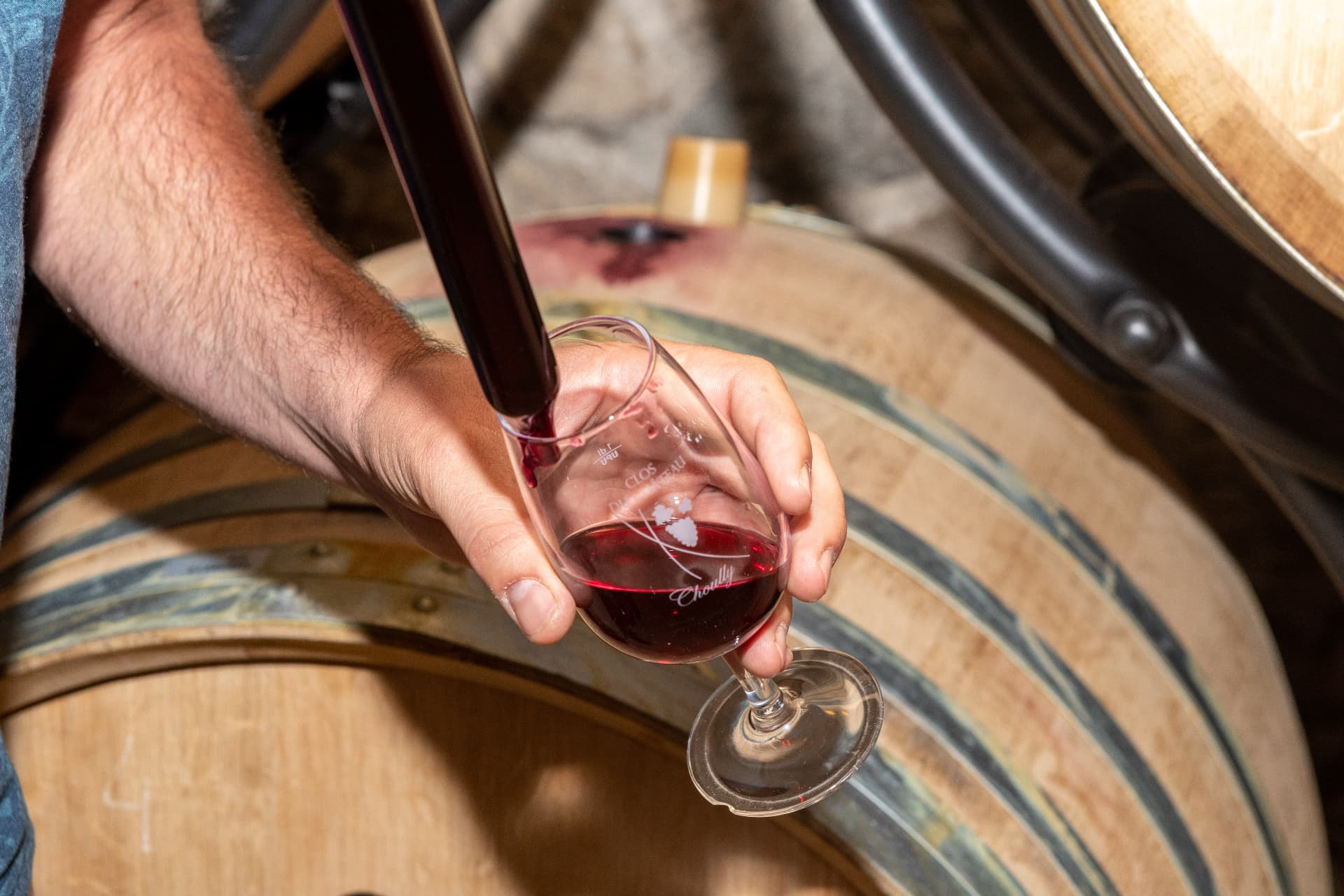Prélèvement de vin rouge au fût dans un verre gravé Clos du Château